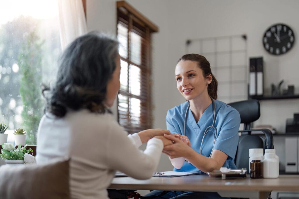 senior care, healthcare insurance and caregiver woman sitting with elderly woman patient laughing and talking while enjoying retirement home. old lady and female nurse hospice with health check form