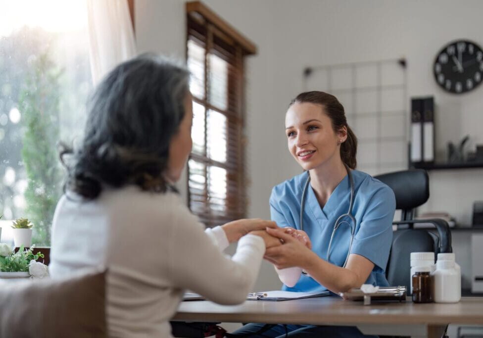 senior care, healthcare insurance and caregiver woman sitting with elderly woman patient laughing and talking while enjoying retirement home. old lady and female nurse hospice with health check form